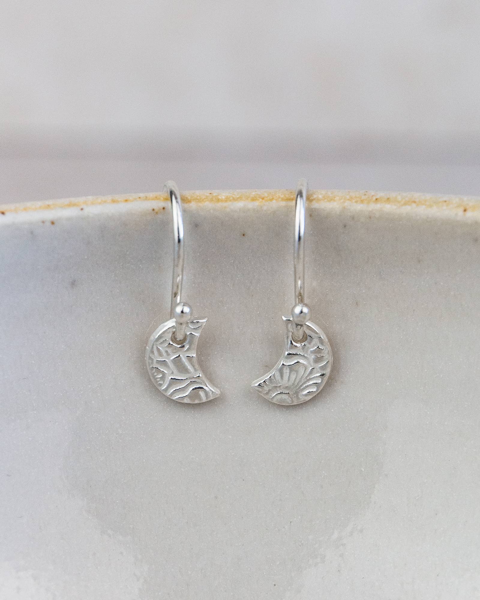 Silver crescent moon earrings on a light gray background