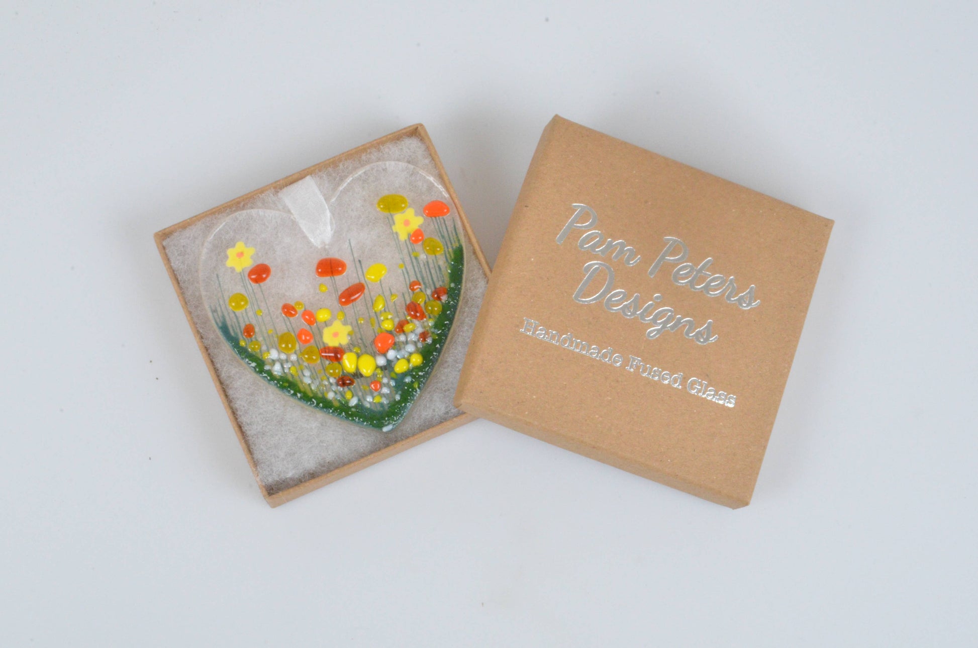 Glass artwork of flowers in a box with 'Petra Polaris Designs' branding on a white background