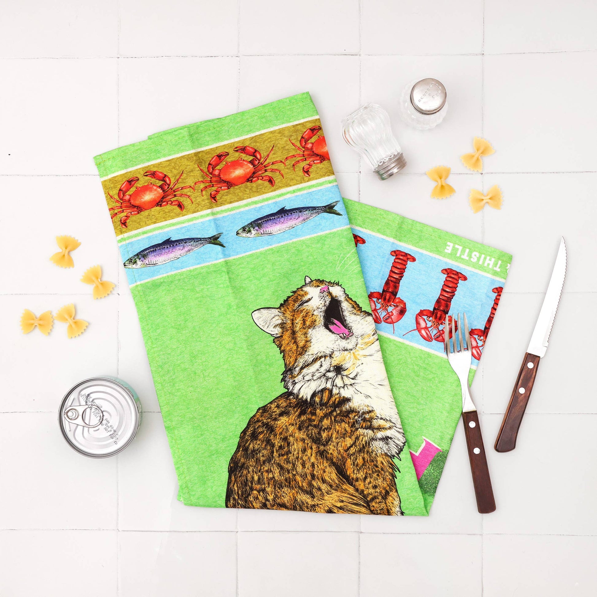 Three colorful kitchen towels with different designs on a white surface.