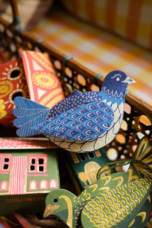 Collection of colorful paper ornaments with a blue bird design on a blurred background