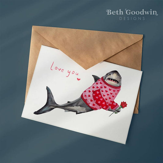 Card with a shark wearing a sweater and holding a rose, with 'Love you' text, on a blue background.