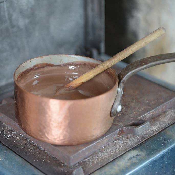 Copper pot with chocolate mixture on a stovetop