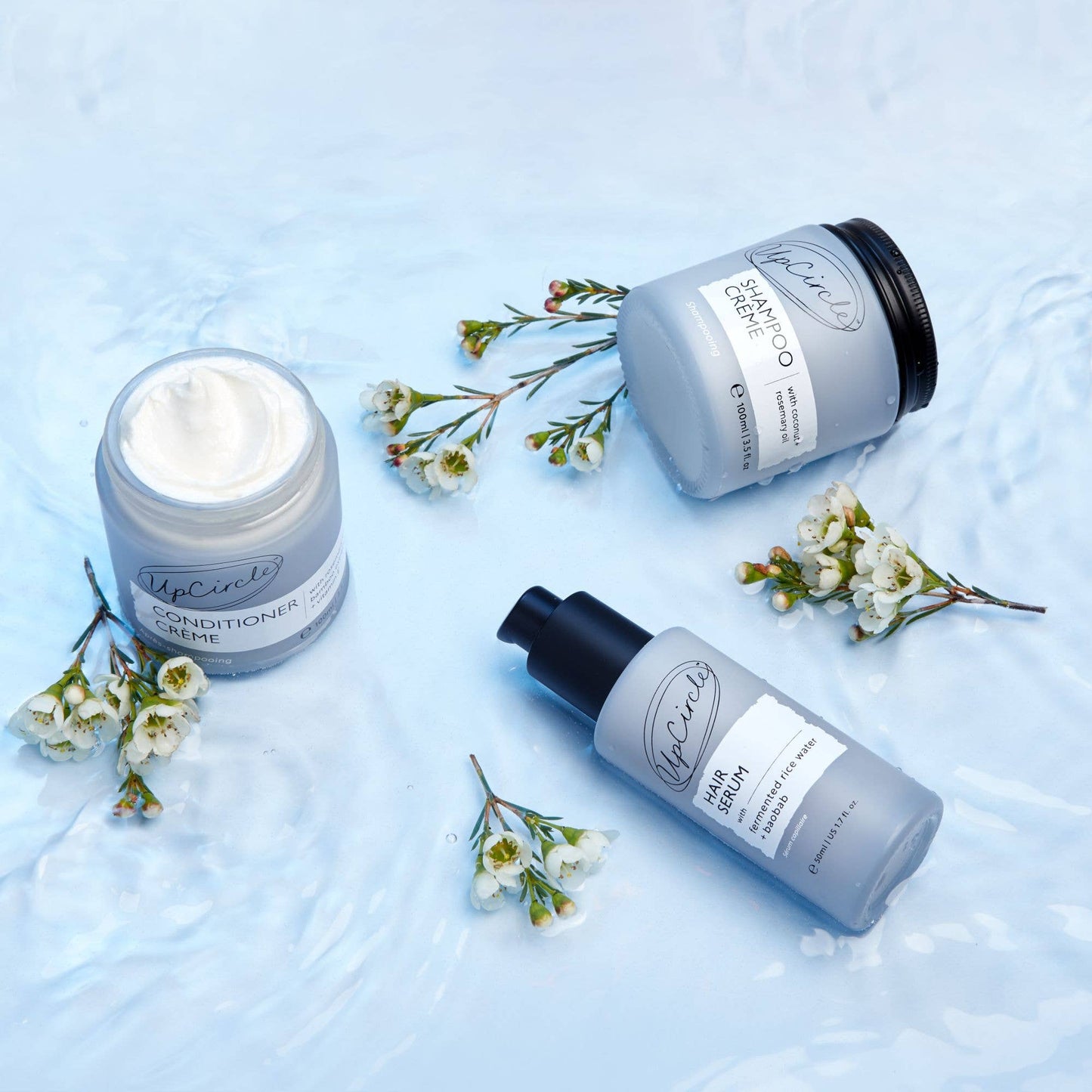 Three hair care products with floral elements on a light blue background