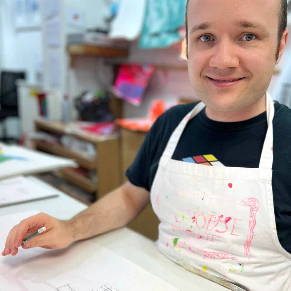 Person wearing a white apron with colorful text in an indoor setting