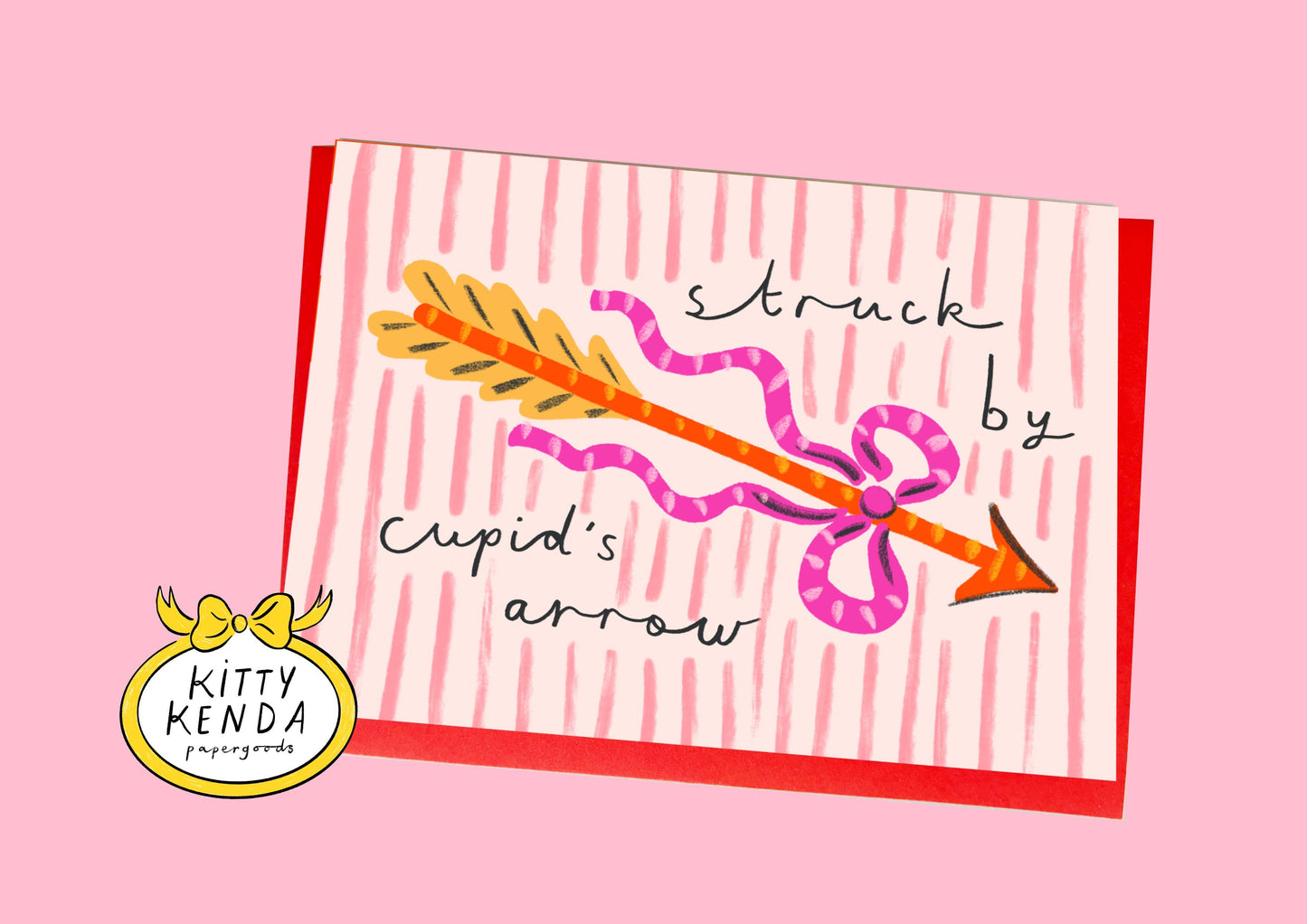 Card with a cartoon arrow and text 'struck by Cupid's arrow' on a pink background, featuring the Kitty Kenda logo.