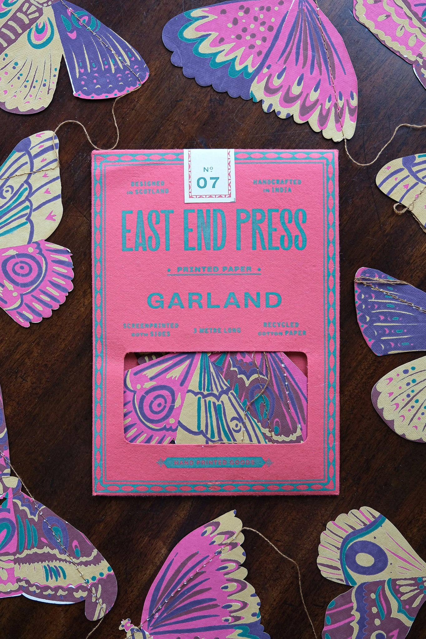 Pink packaging of East End Press Garland with colorful butterfly decorations on a wooden surface