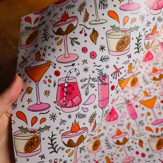 Patterned paper with colorful drink illustrations held by a hand.