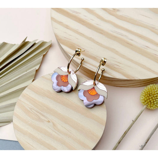 Pair of floral earrings on a wooden surface with natural elements.