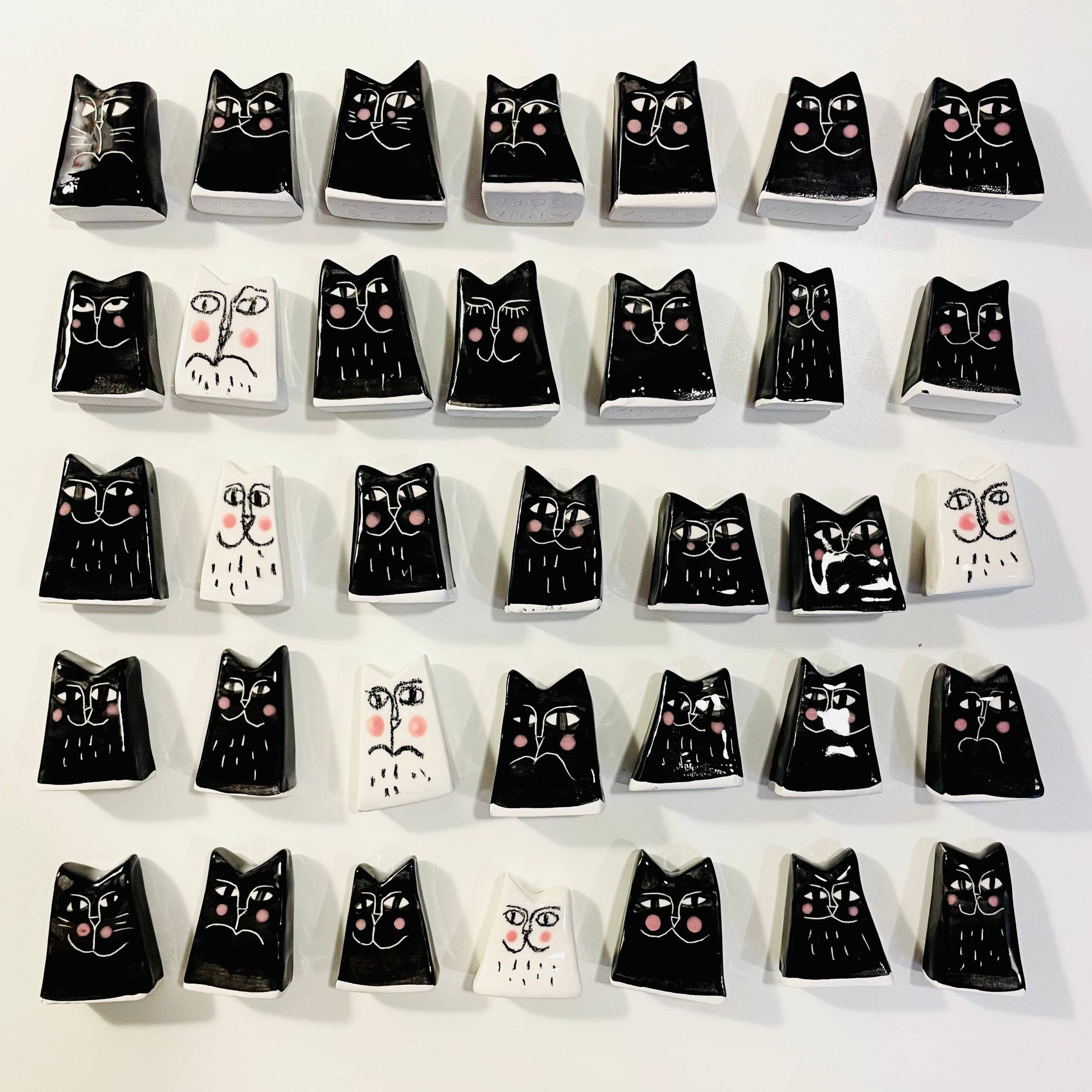Collection of black cat-shaped ceramic tiles with white backgrounds on a white surface