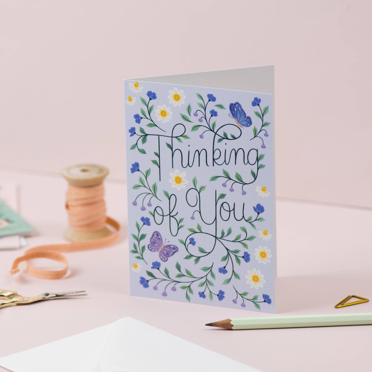 Greeting card with floral design and 'Thinking of You' text on a pink background