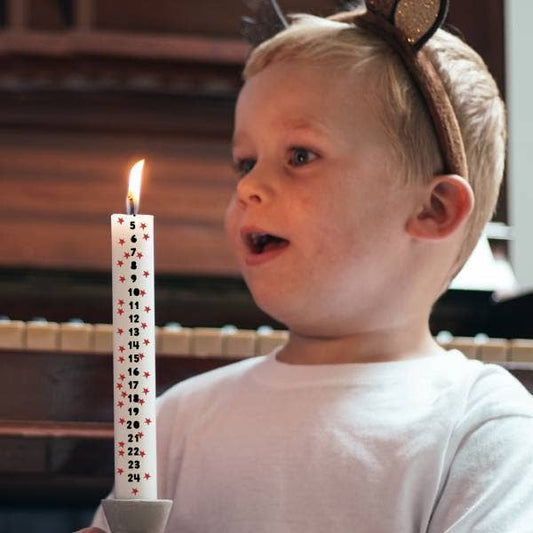Child with a birthday candle featuring numbers, wearing a headband with animal ears.