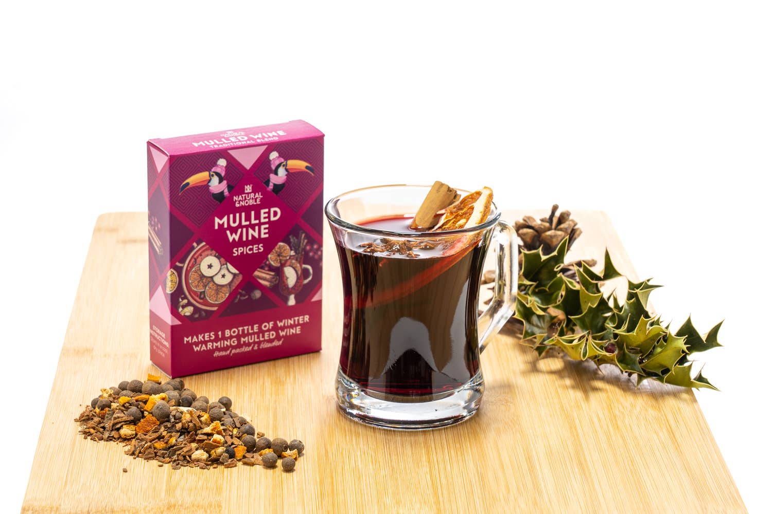 Mug of mulled wine with spices and a box of mulled wine mix on a wooden board.