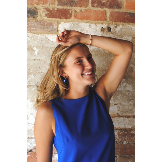 Woman in a blue dress posing against a brick wall