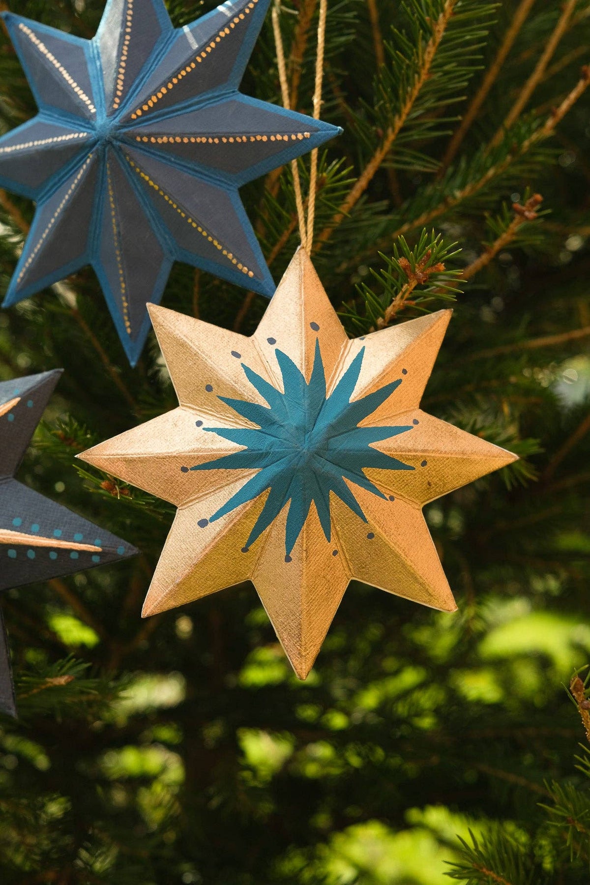 Star-shaped ornaments on a Christmas tree with blue and gold colors.