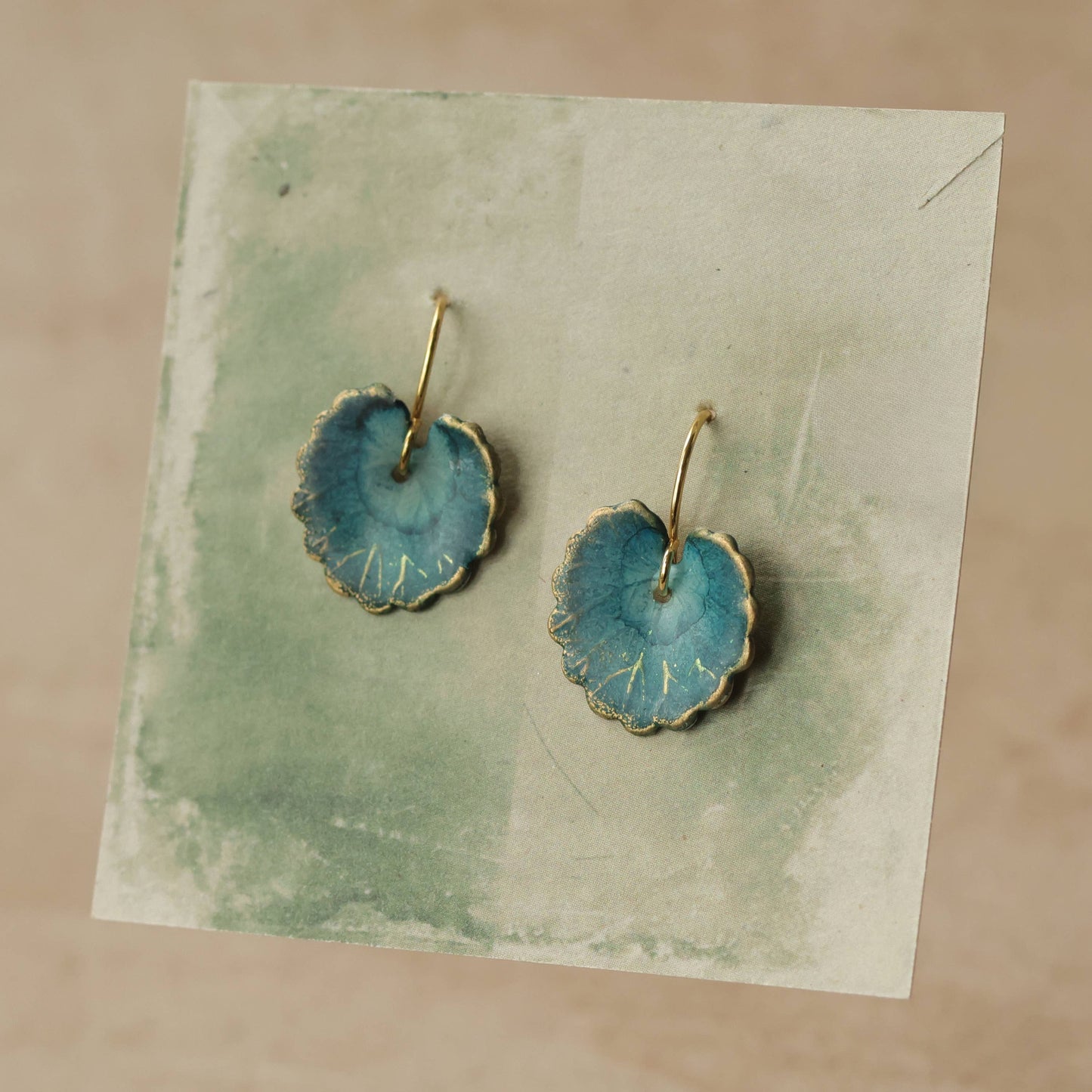 Pair of blue earrings with gold accents on a textured card