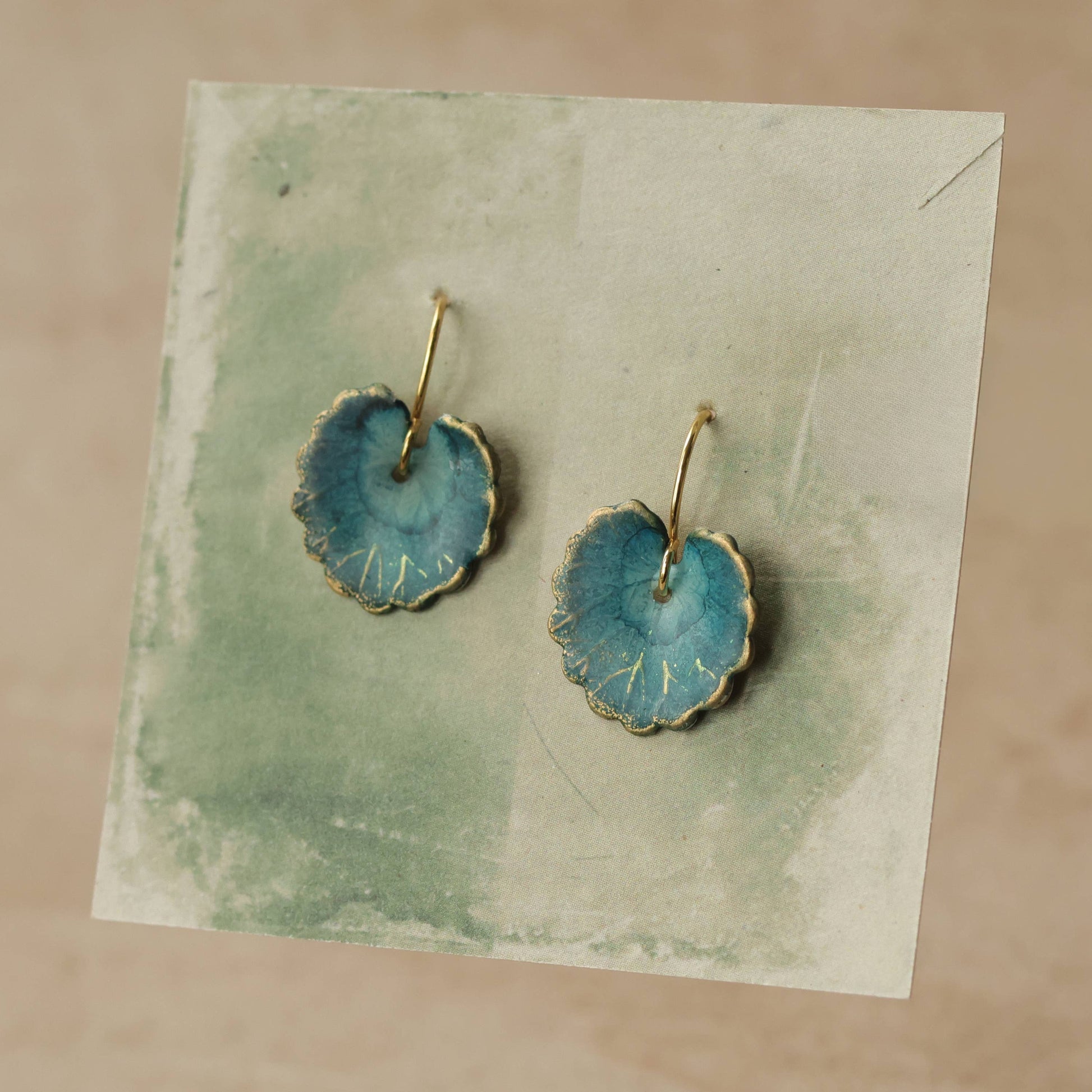 Pair of blue earrings with gold accents on a textured card
