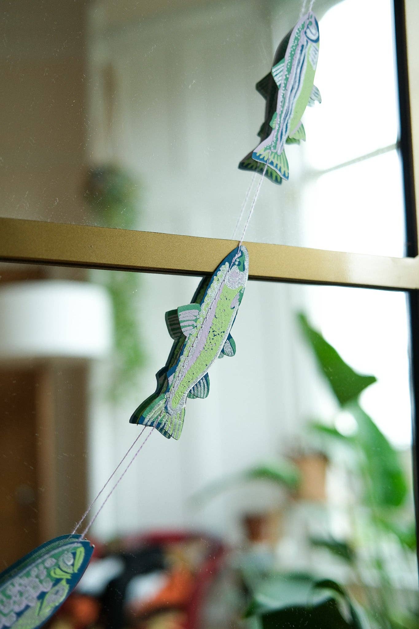 Decorative fish-shaped objects hanging on a string with a blurred indoor background