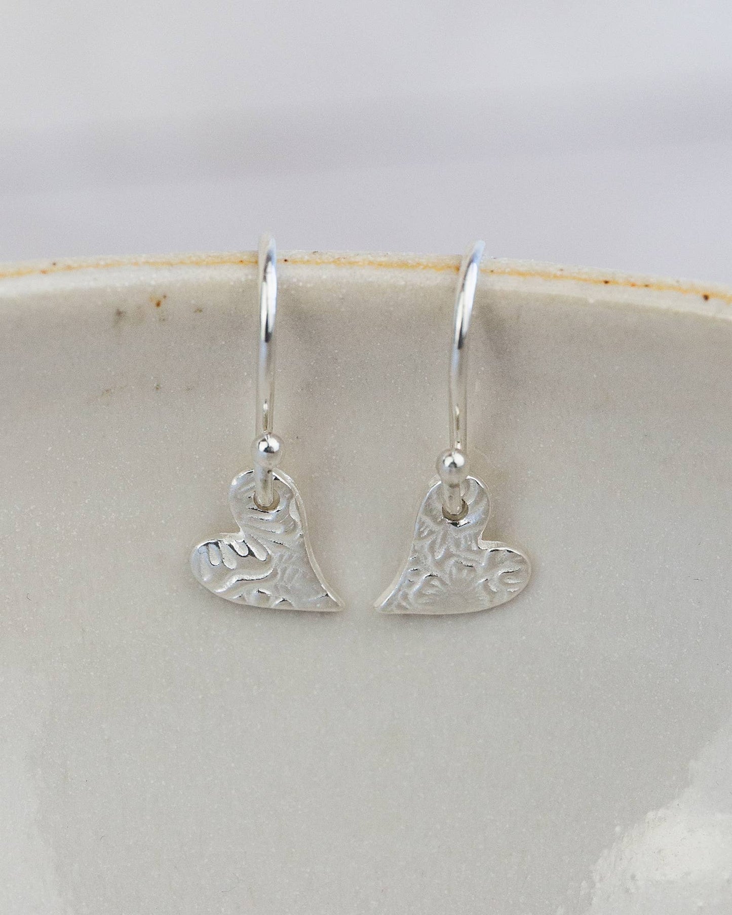 Silver heart-shaped earrings on a white dish