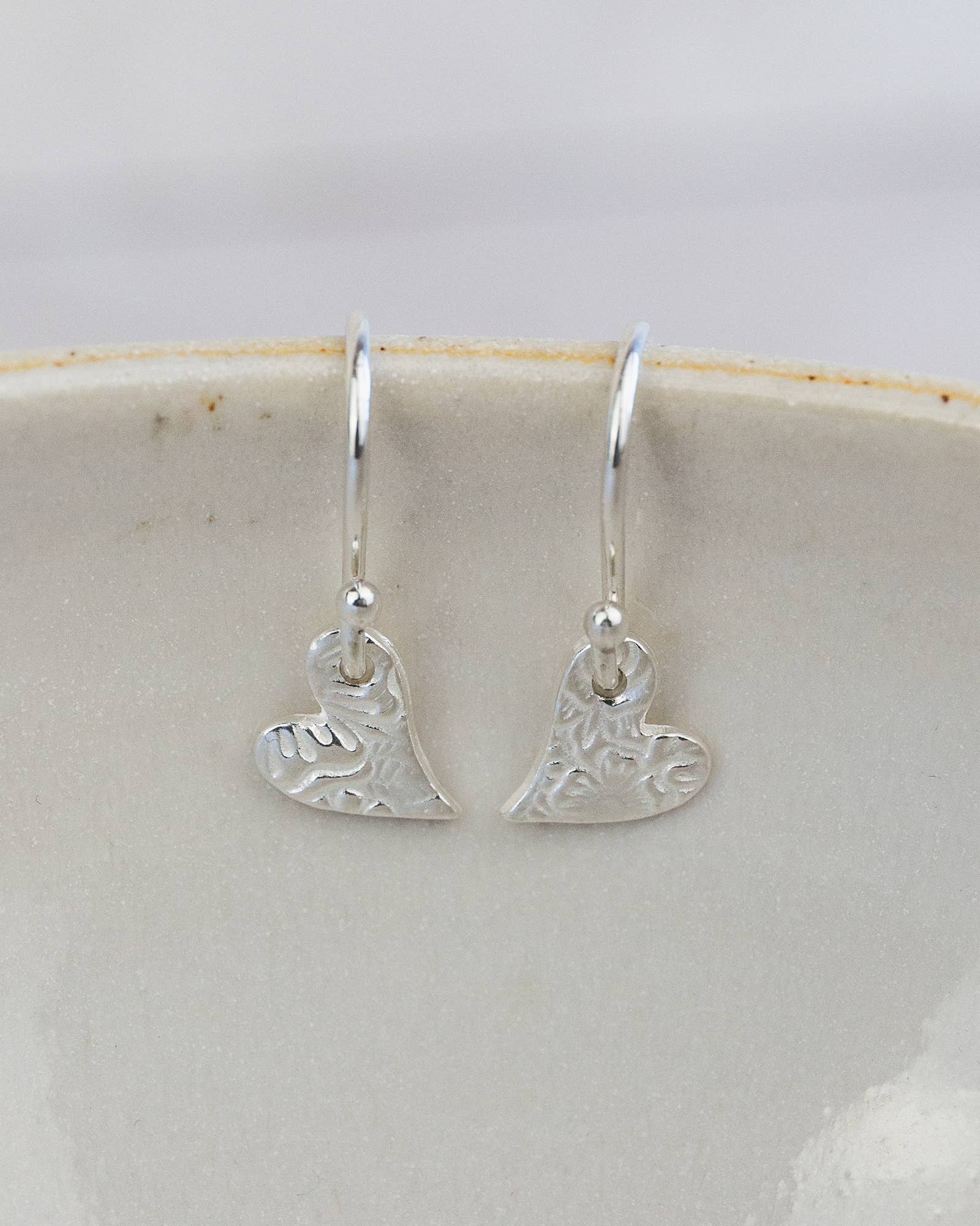 Silver heart-shaped earrings on a white dish
