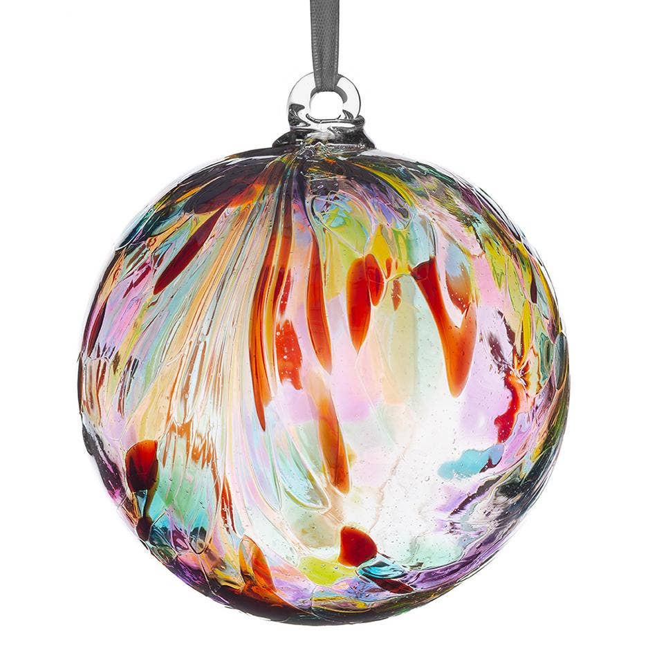 A hand-blown glass Christmas ornament with a colorful swirl pattern of red, orange, yellow, green, pink, and blue on a clear glass sphere, hanging from a black ribbon.