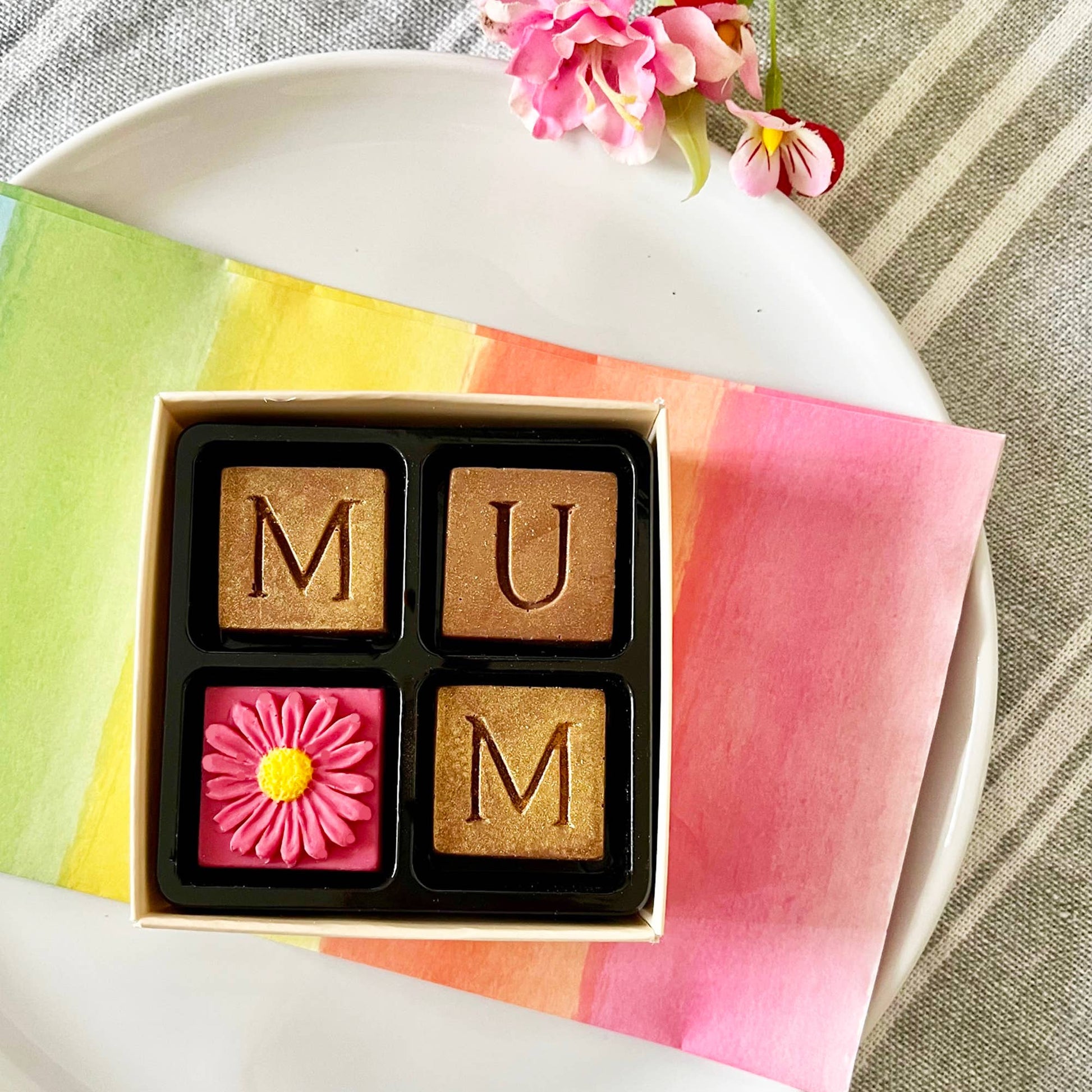 Chocolate bars with 'MUM' and a pink flower design on a colorful napkin.