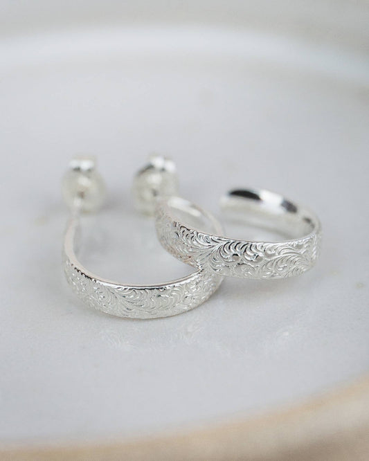 Silver hoop earrings with intricate designs on a light background