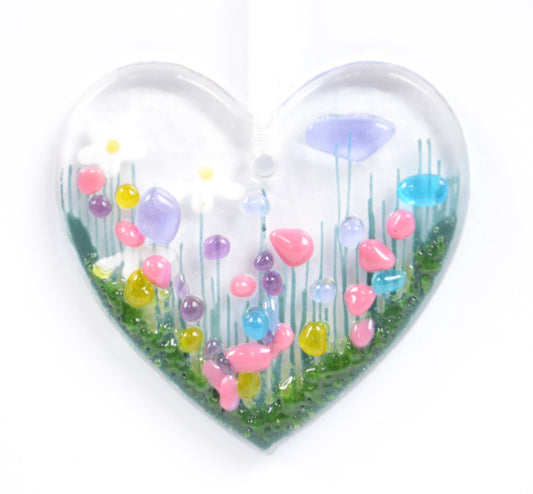 Heart-shaped transparent container with colorful glass flowers on a white background