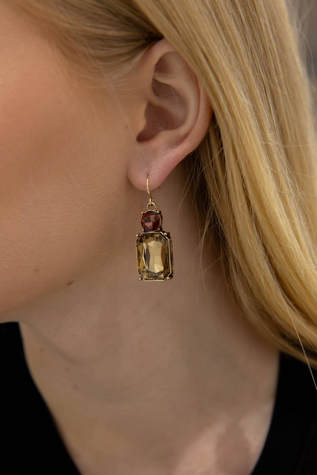 Close-up of a person wearing a gold earring with gemstones.