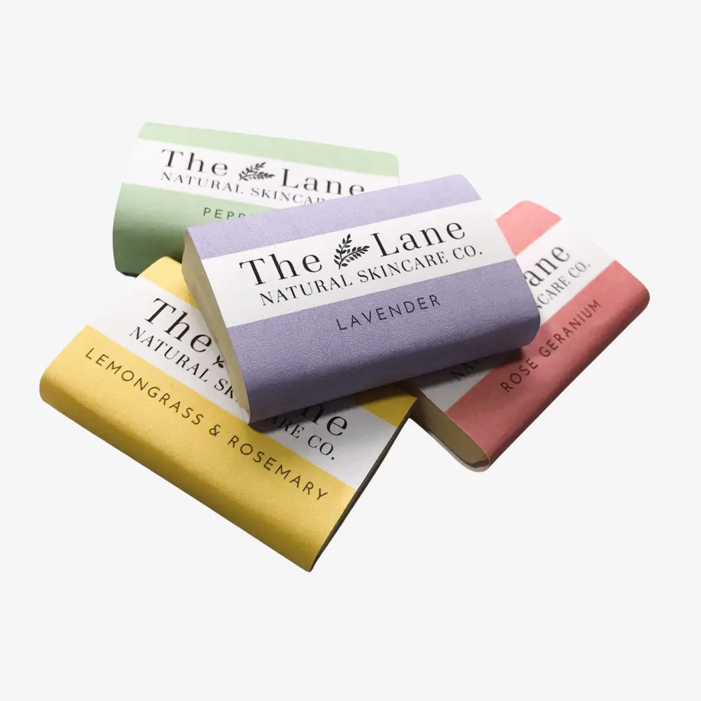 Four bars of soap from The Lane Natural Skincare Co. on a white background