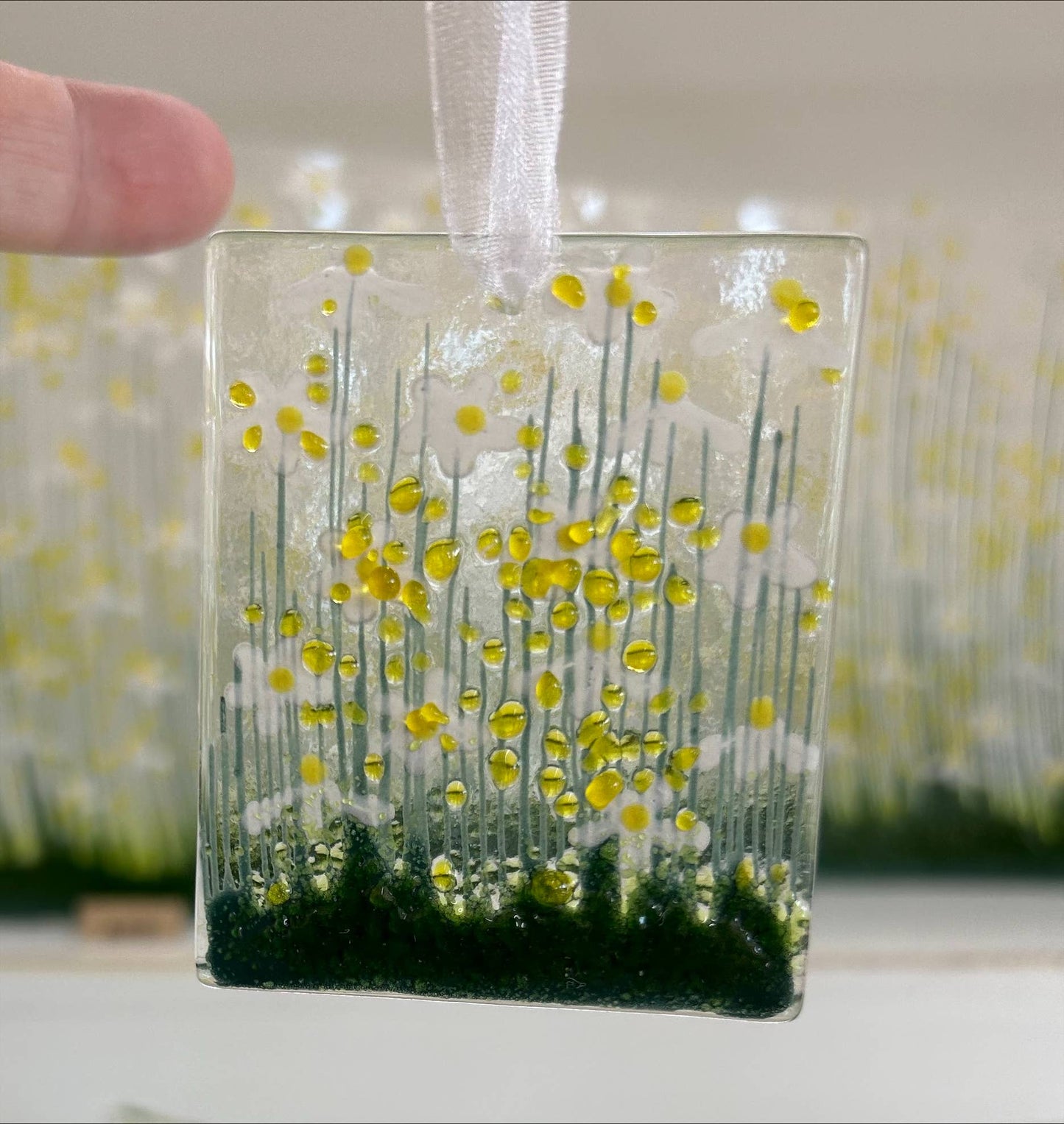 Decorative glass panel with yellow floral design held by a hand