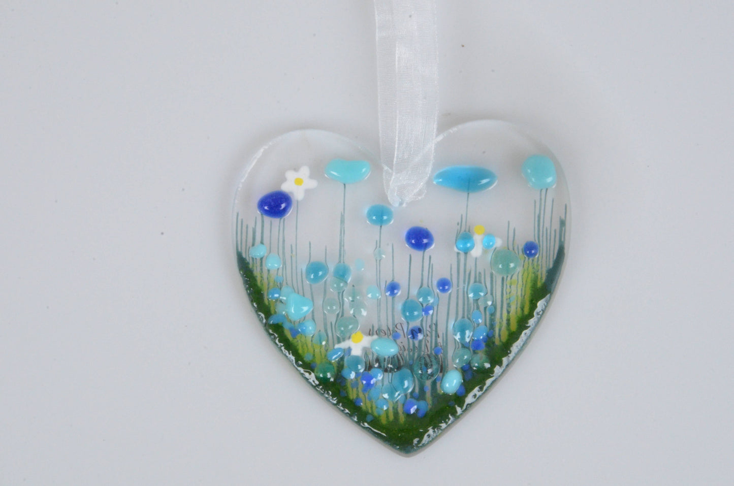 Heart-shaped glass ornament with blue and green floral design on a white background