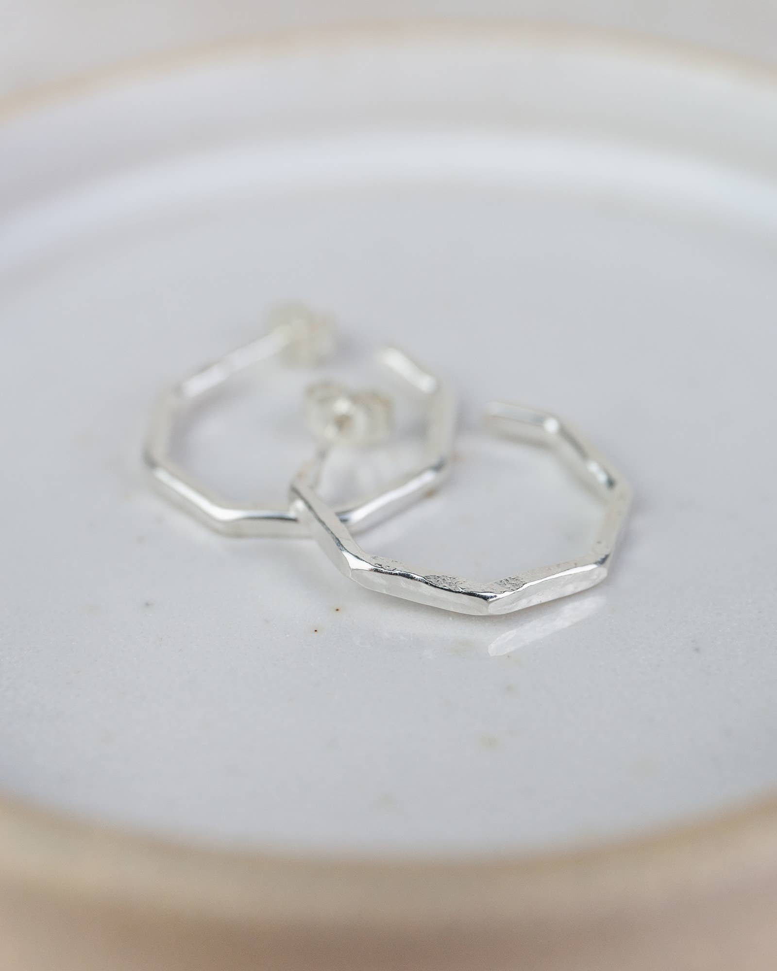 Silver hoop earrings on a light beige plate