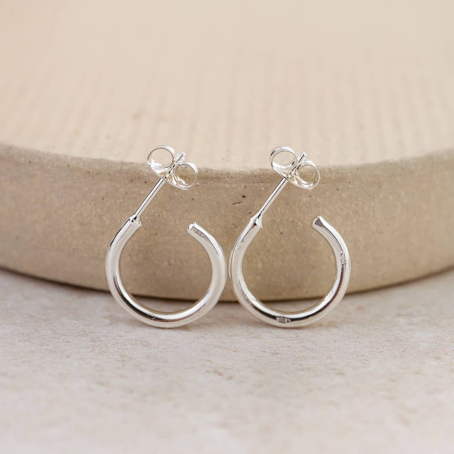 Silver hoop earrings on a neutral background