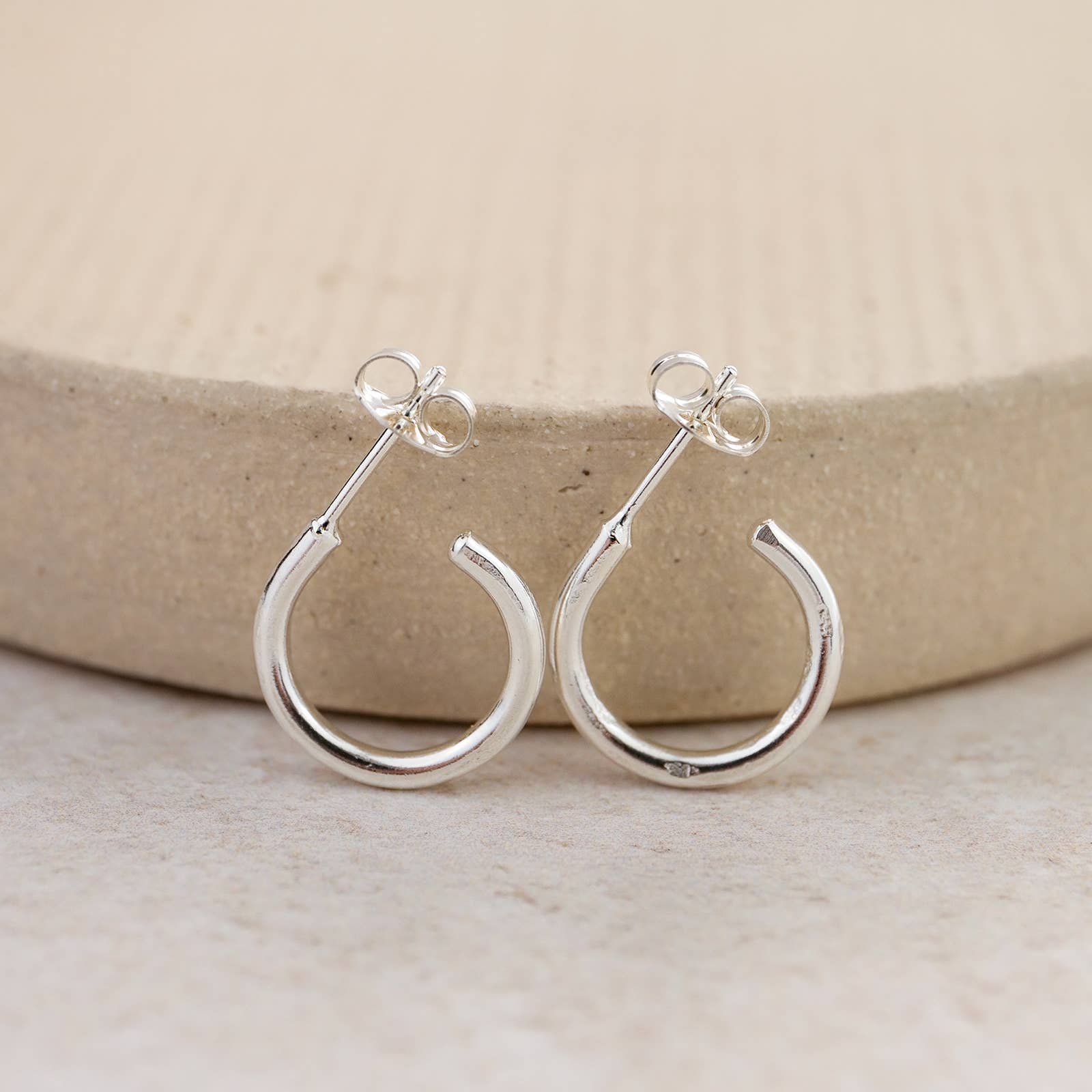 Silver hoop earrings on a neutral background