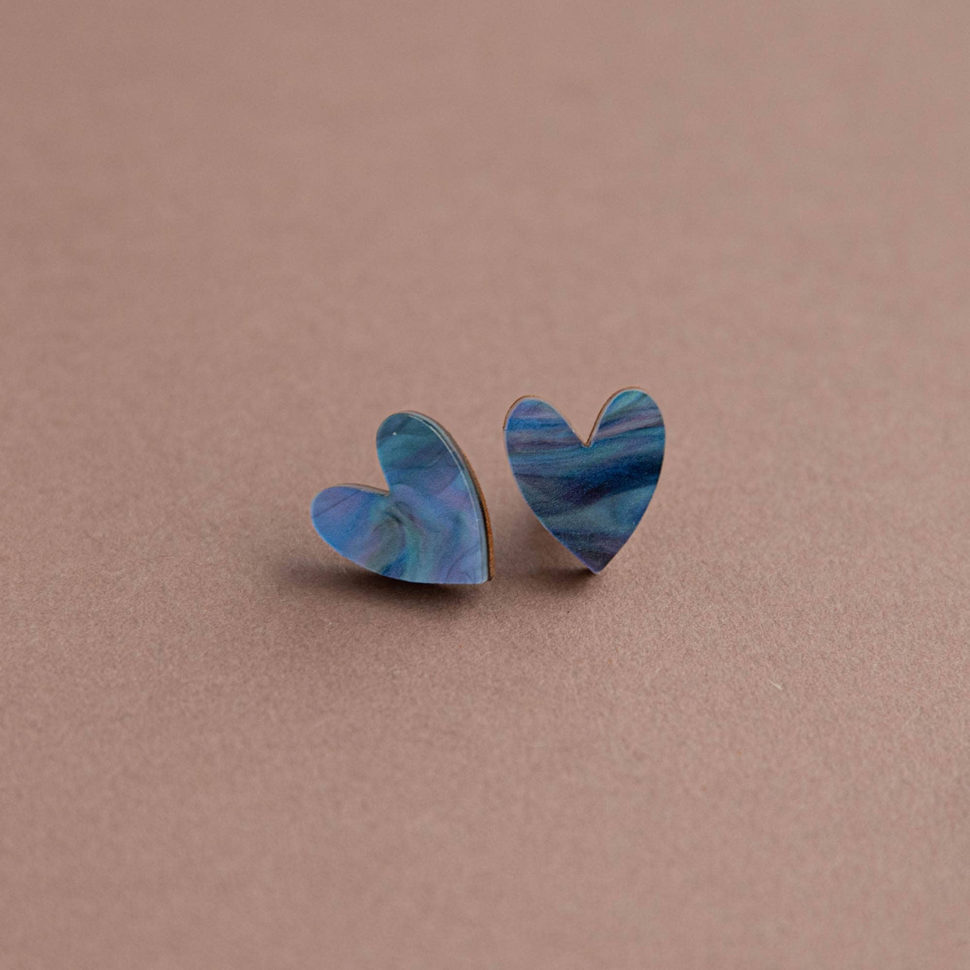 Heart-shaped earrings with blue marbled design on a brown background