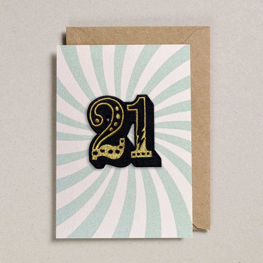 Greeting card with number 21 design on a light blue and white striped background, featuring a brown envelope.