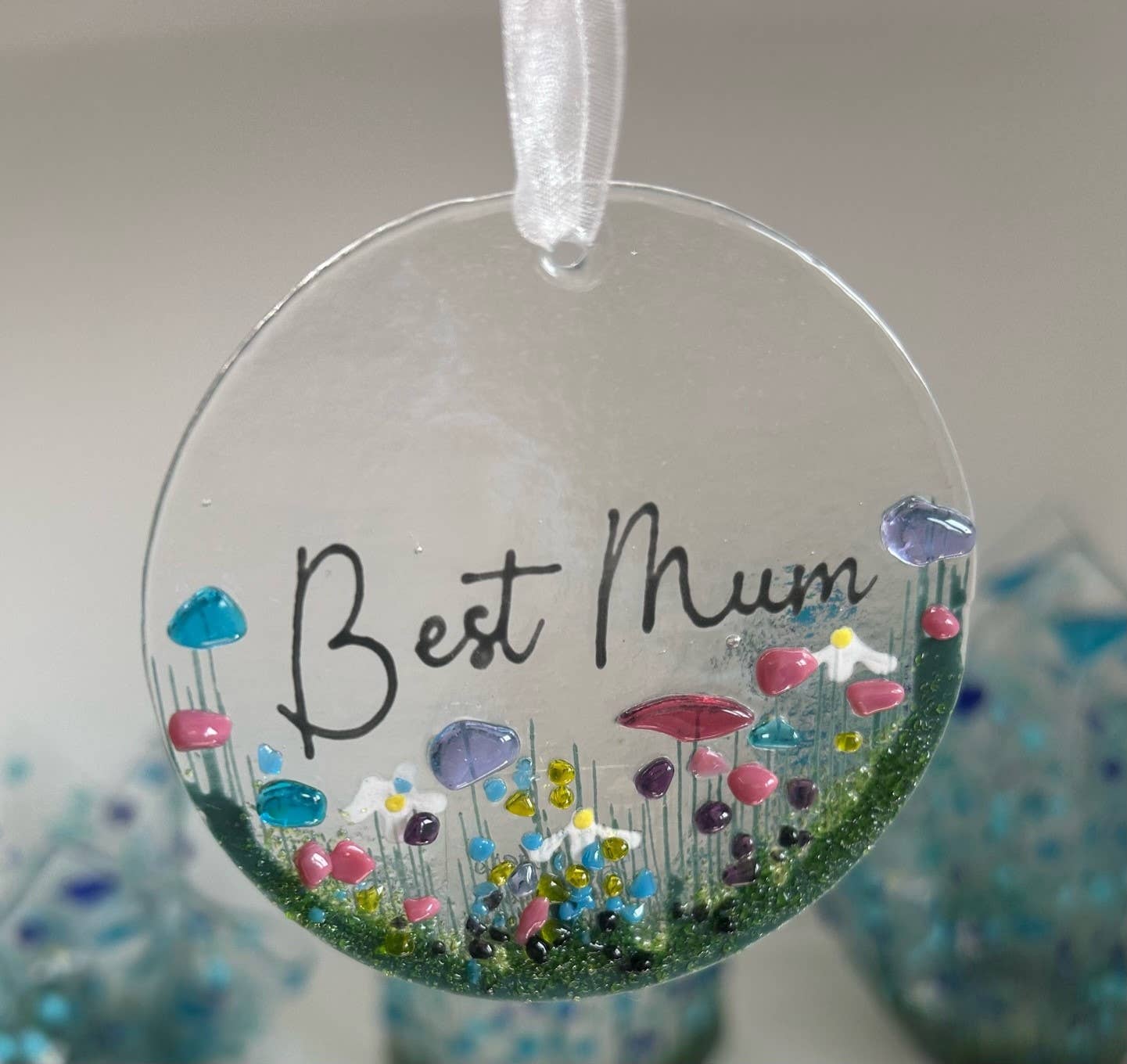 Round decorative item with 'Best Mum' text and colorful flowers on a white background
