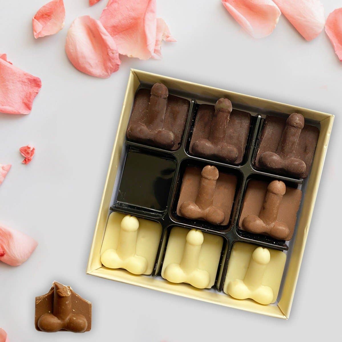 Box of chocolate figurines on a light surface with pink flower petals.