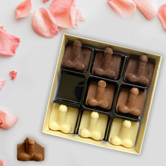 Box of chocolate figurines on a light surface with pink flower petals.