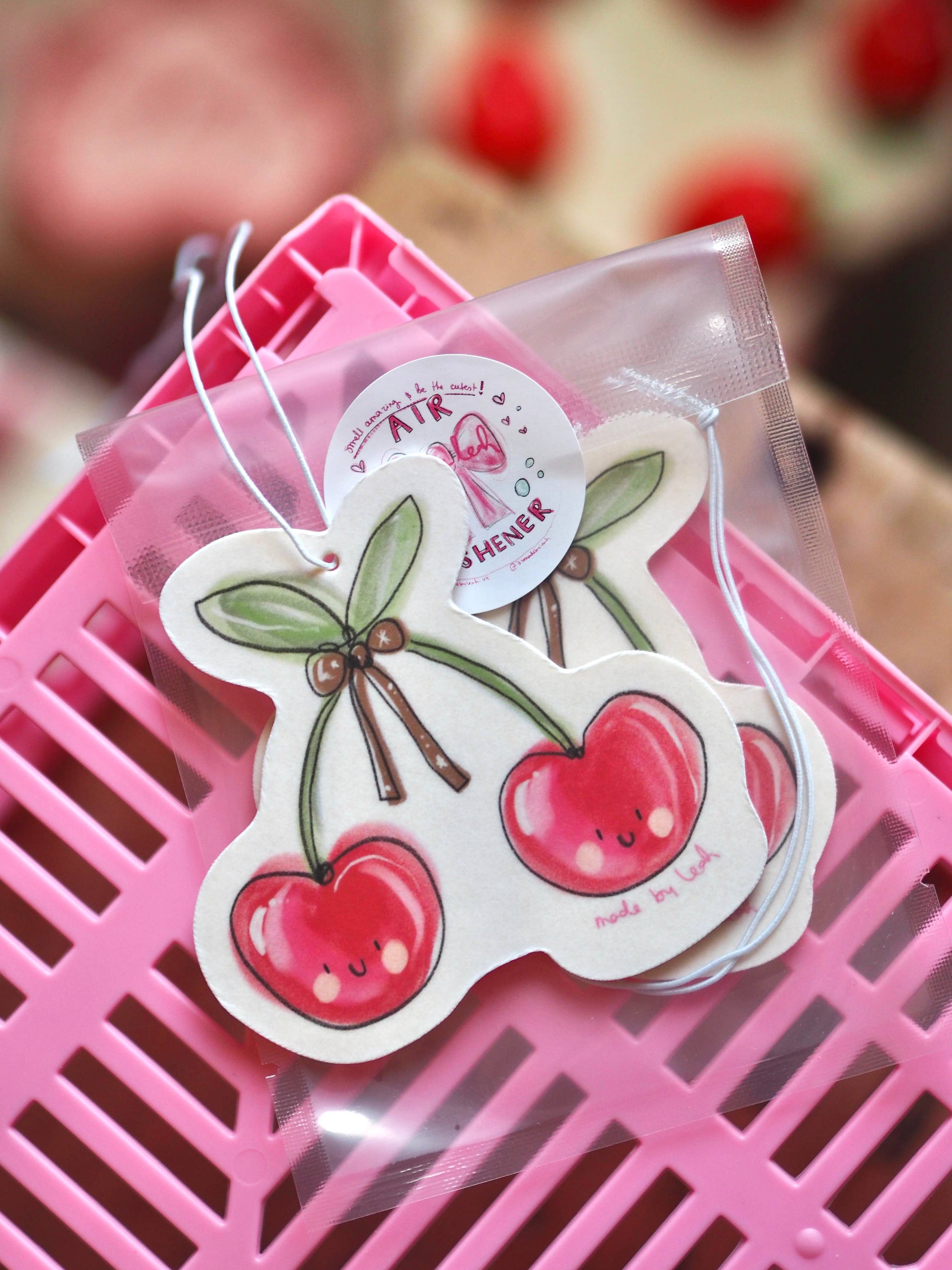 Cartoon cherry-themed air freshener on a pink surface