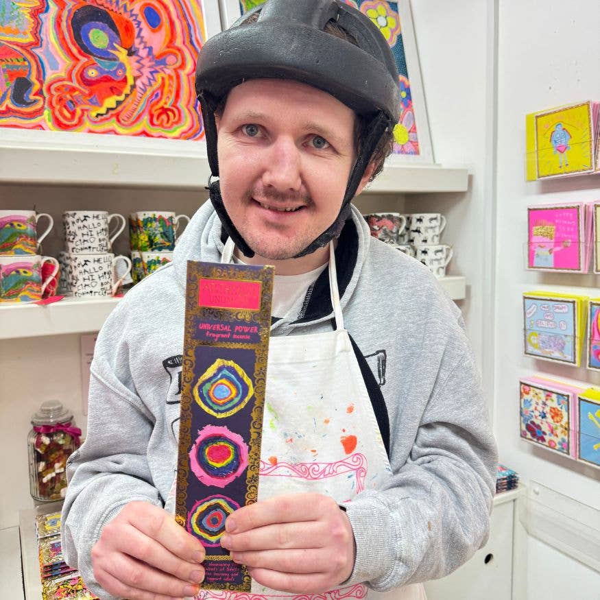 Person wearing a helmet and apron, holding a colorful belt in a store setting.