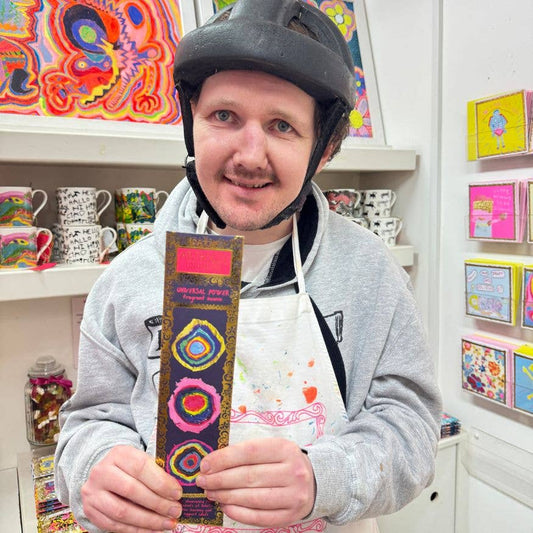 Person wearing a helmet and apron, holding a colorful belt in a store setting.