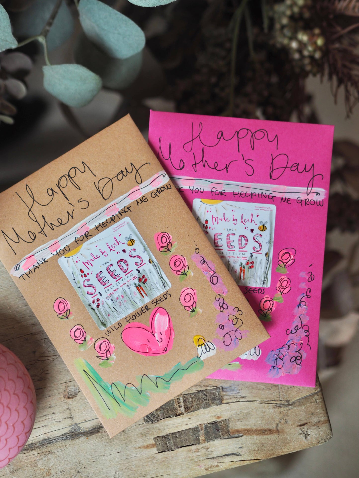 Two Mother's Day cards on a wooden surface with decorative elements.