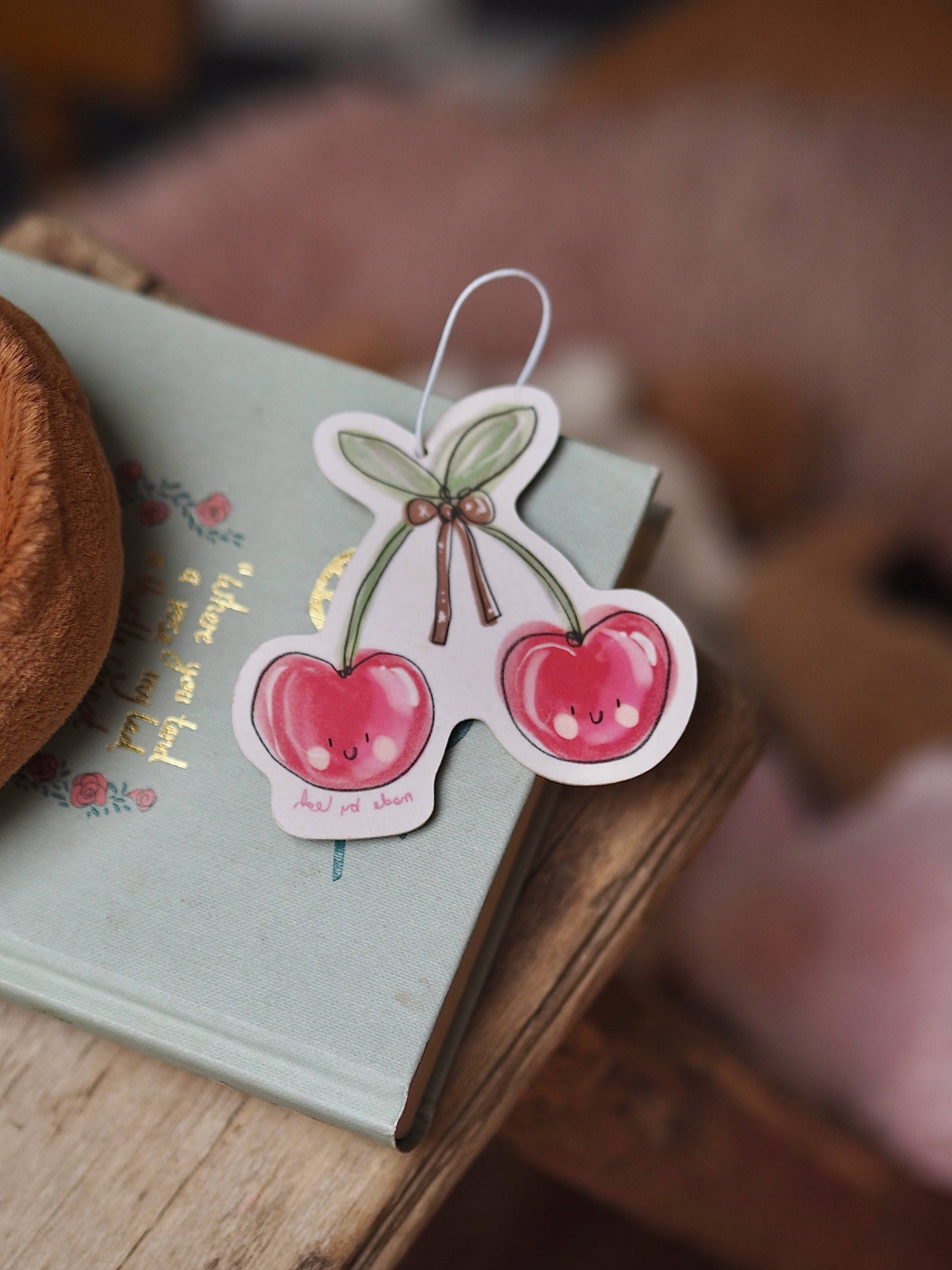 Cherry-themed bookmark on a notebook with a blurred background