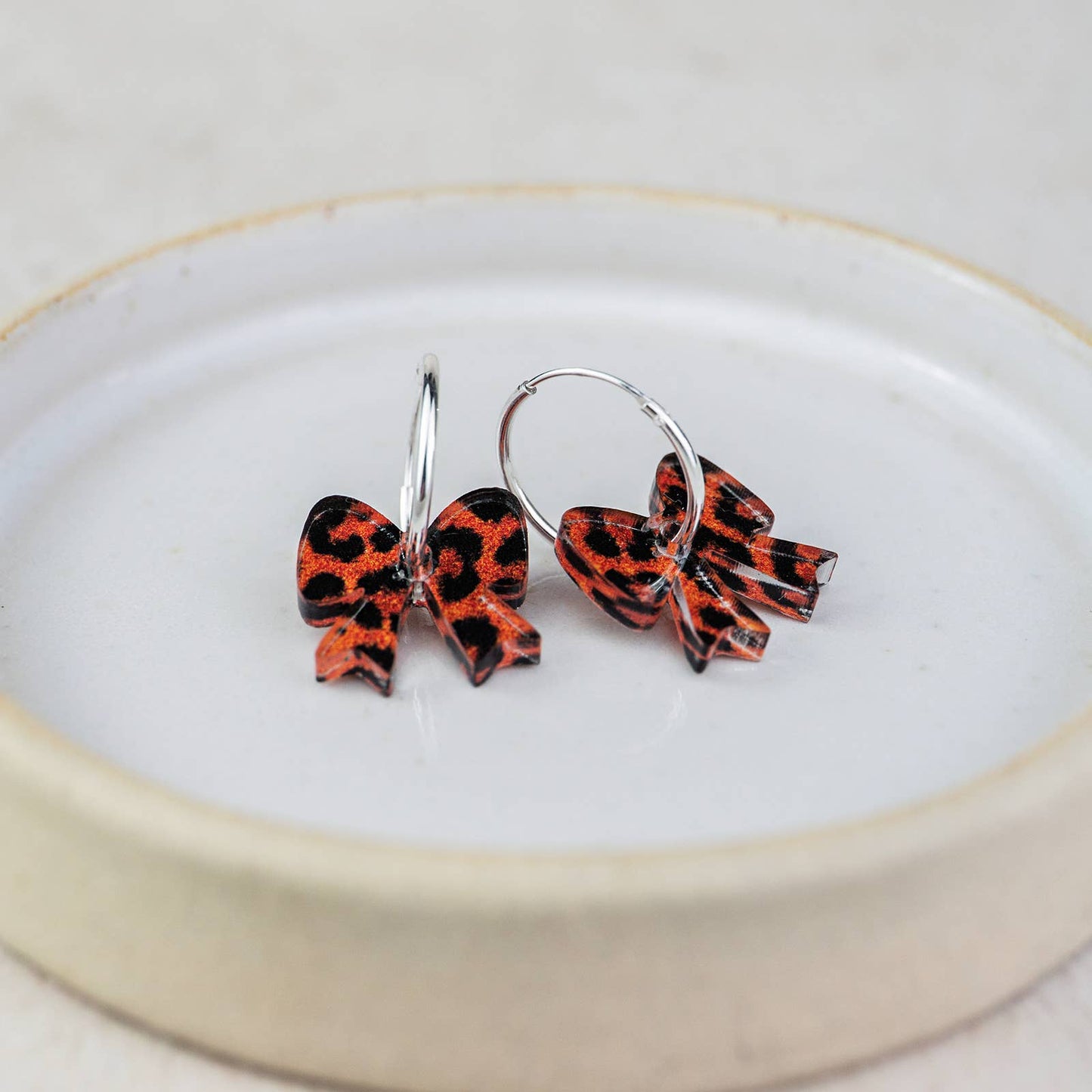 Pair of red and black bow-shaped earrings on a white plate with a gold rim.