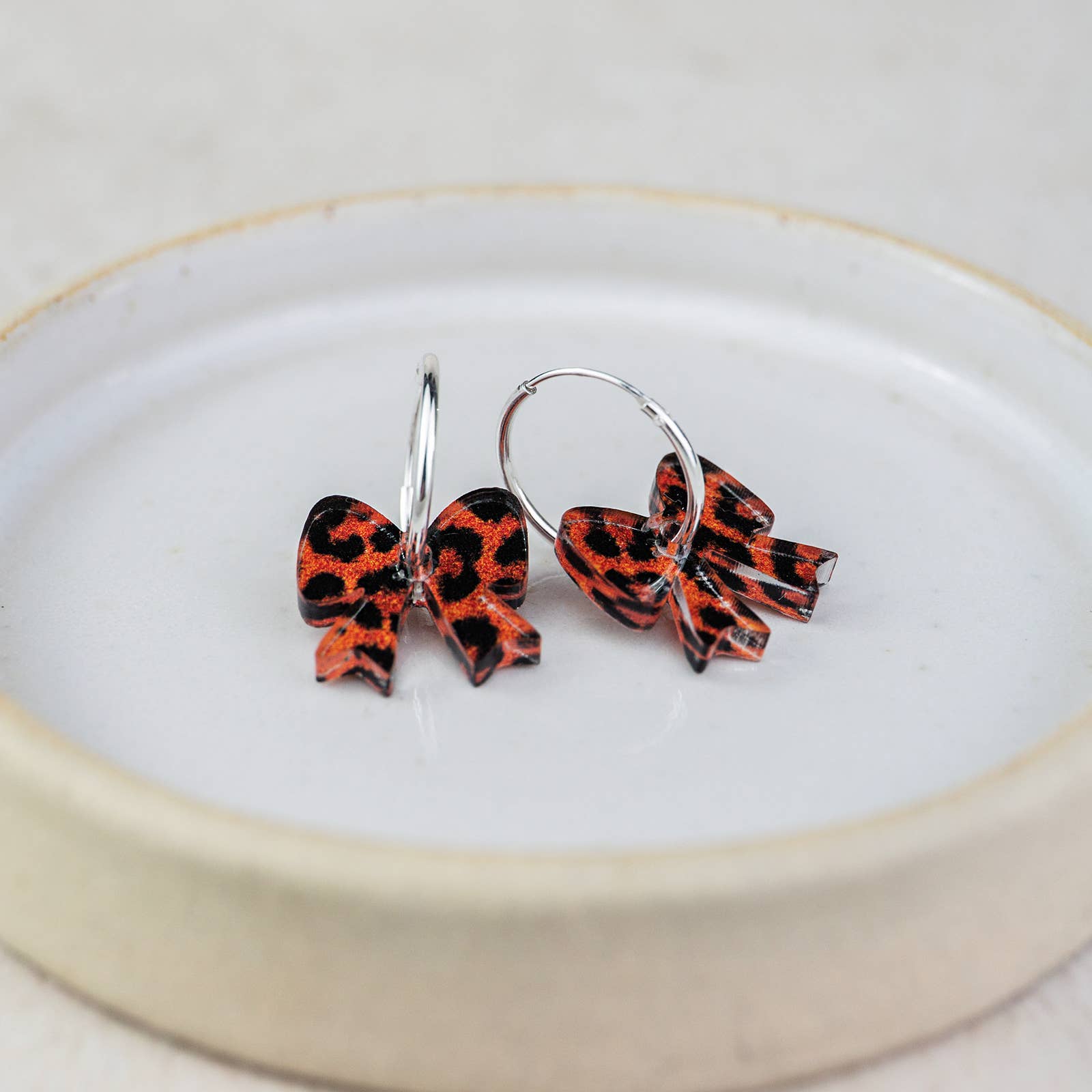Pair of red and black bow-shaped earrings on a white plate with a gold rim.