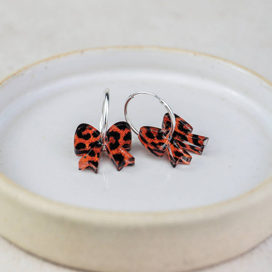 Pair of red and black bow-shaped earrings on a white plate with a gold rim.
