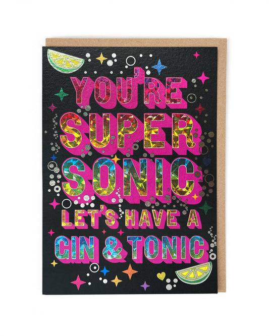 A card with the phrase "You're supersonic let's have a gin & tonic" in a sparkly font surrounded by bubbles, limes and sparkles.