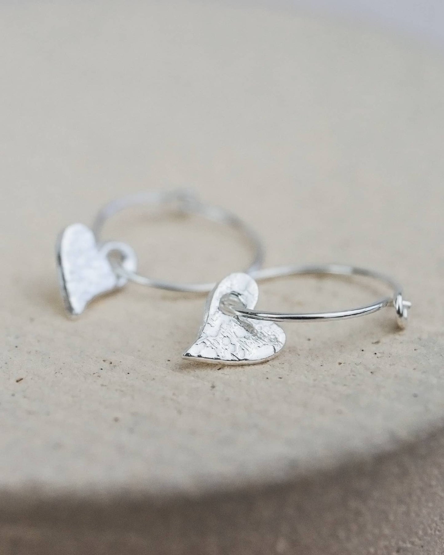 Silver bracelet with heart-shaped ends on a beige surface