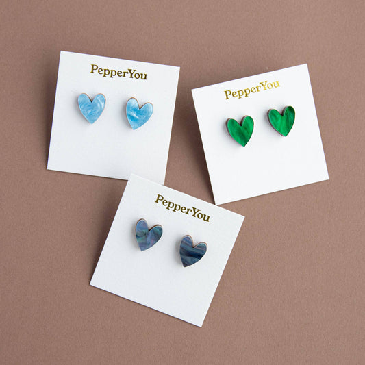 Heart-shaped earrings on 'PepperYou' branded cards against a brown background